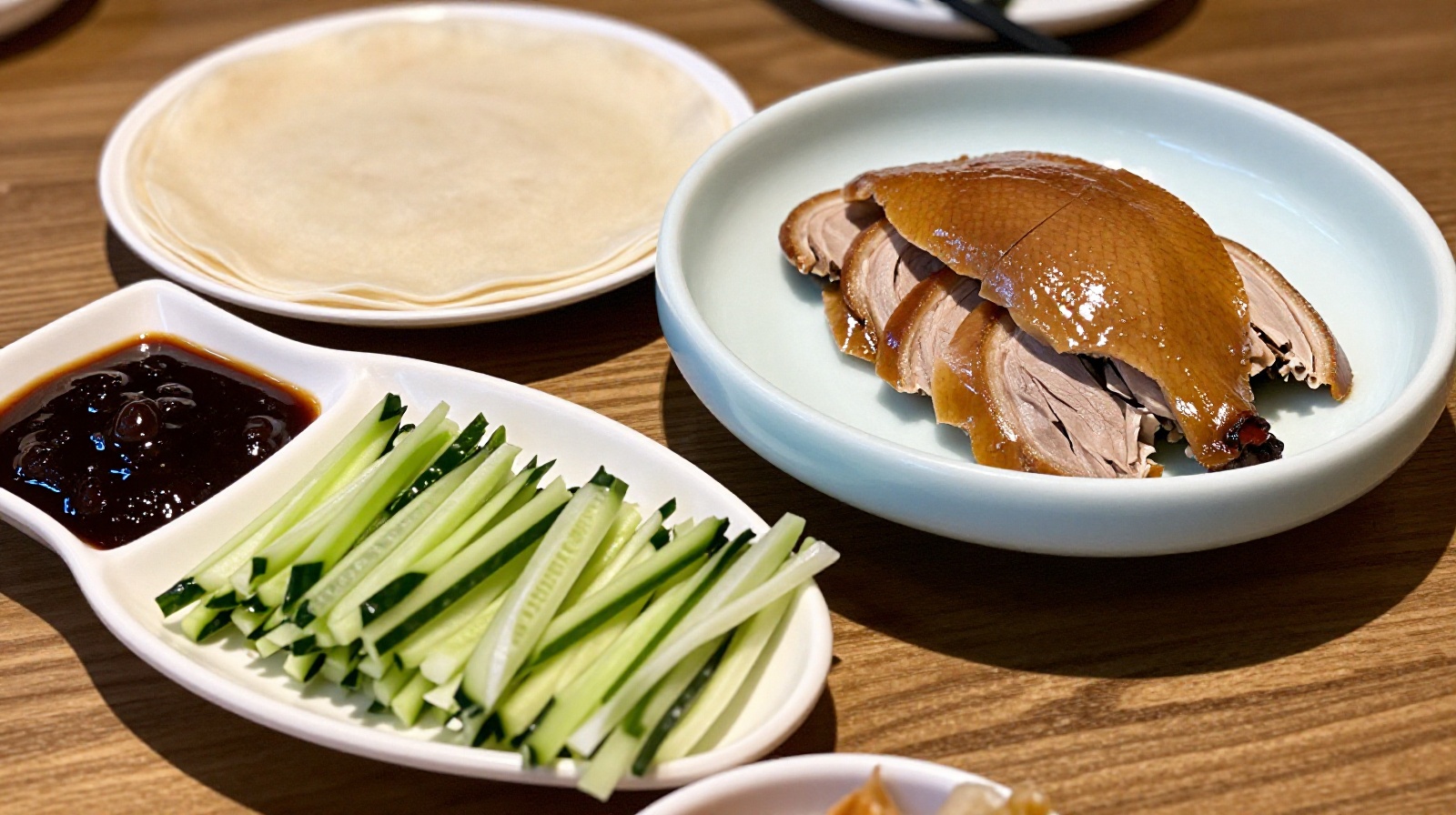 Traditional setup for eating Peking duck with pancakes, sauce, and vegetables on a dining table