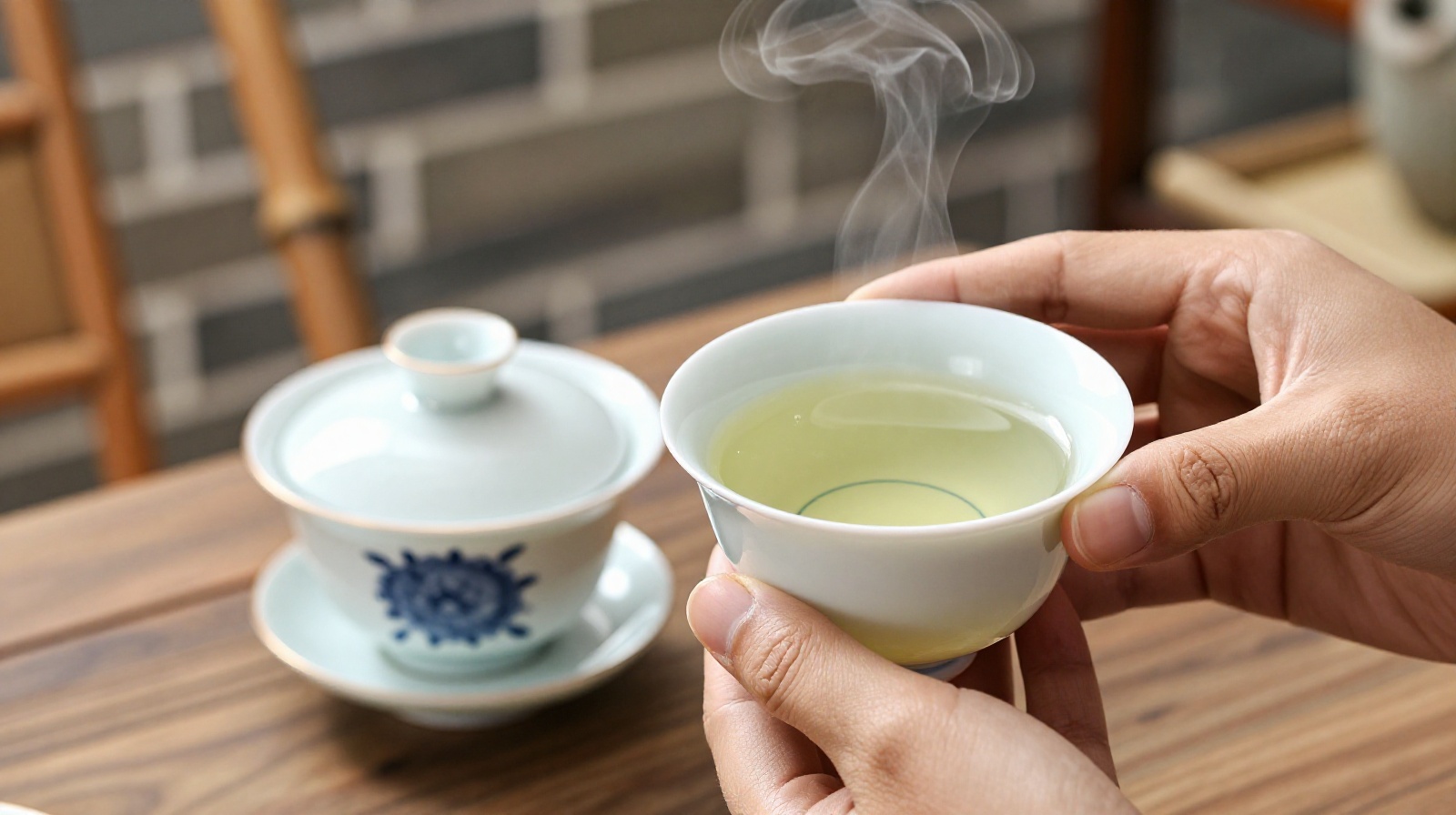 Close-up of hands holding a traditional three-part Gaiwan teacup on a bamboo chair in Chengdu