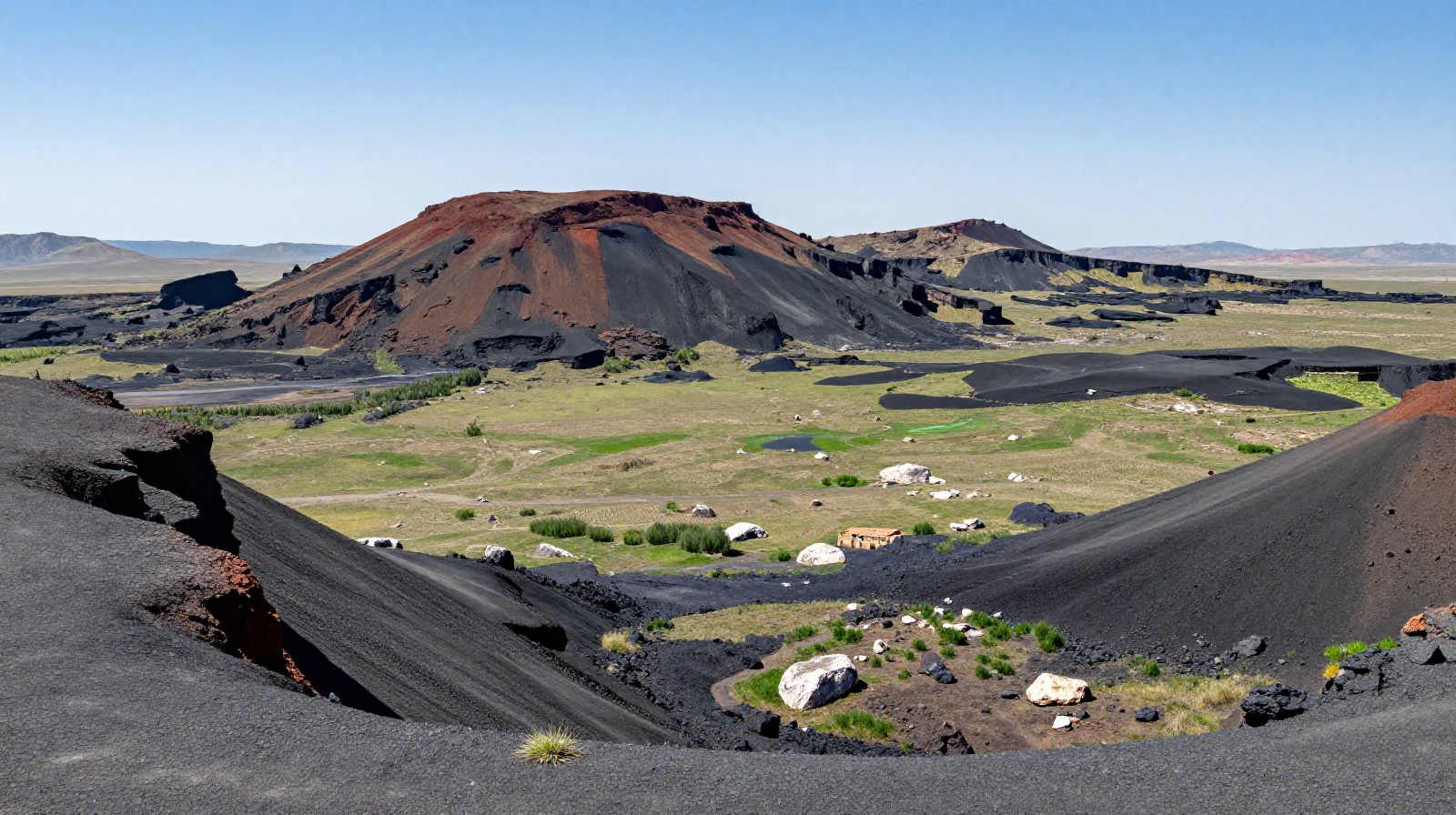 Volcanic crater landscape in Inner Mongolia with black rocks and green reeds