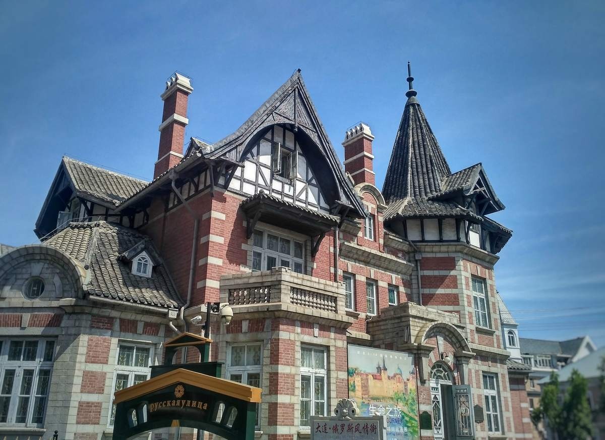 Zhongshan Square in Dalian featuring a Russian Orthodox church with golden onion domes amidst historic yellow and red buildings under a sunny sky