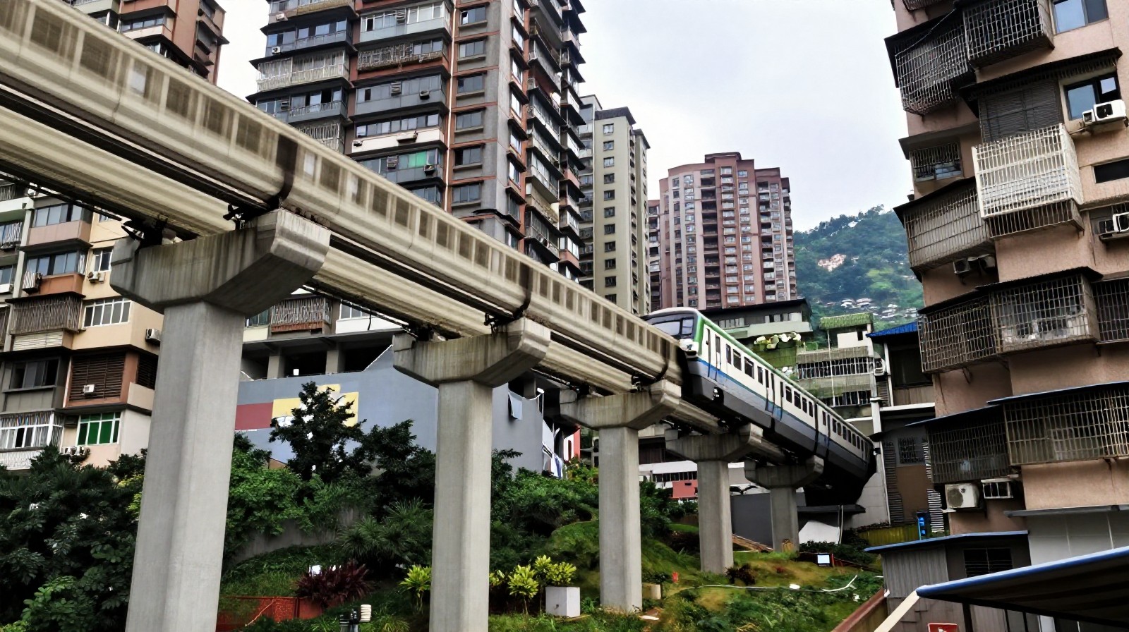 Low angle view of Chongqing's light rail track embedded into a high-rise residential building showing the complex 3D urban structure.