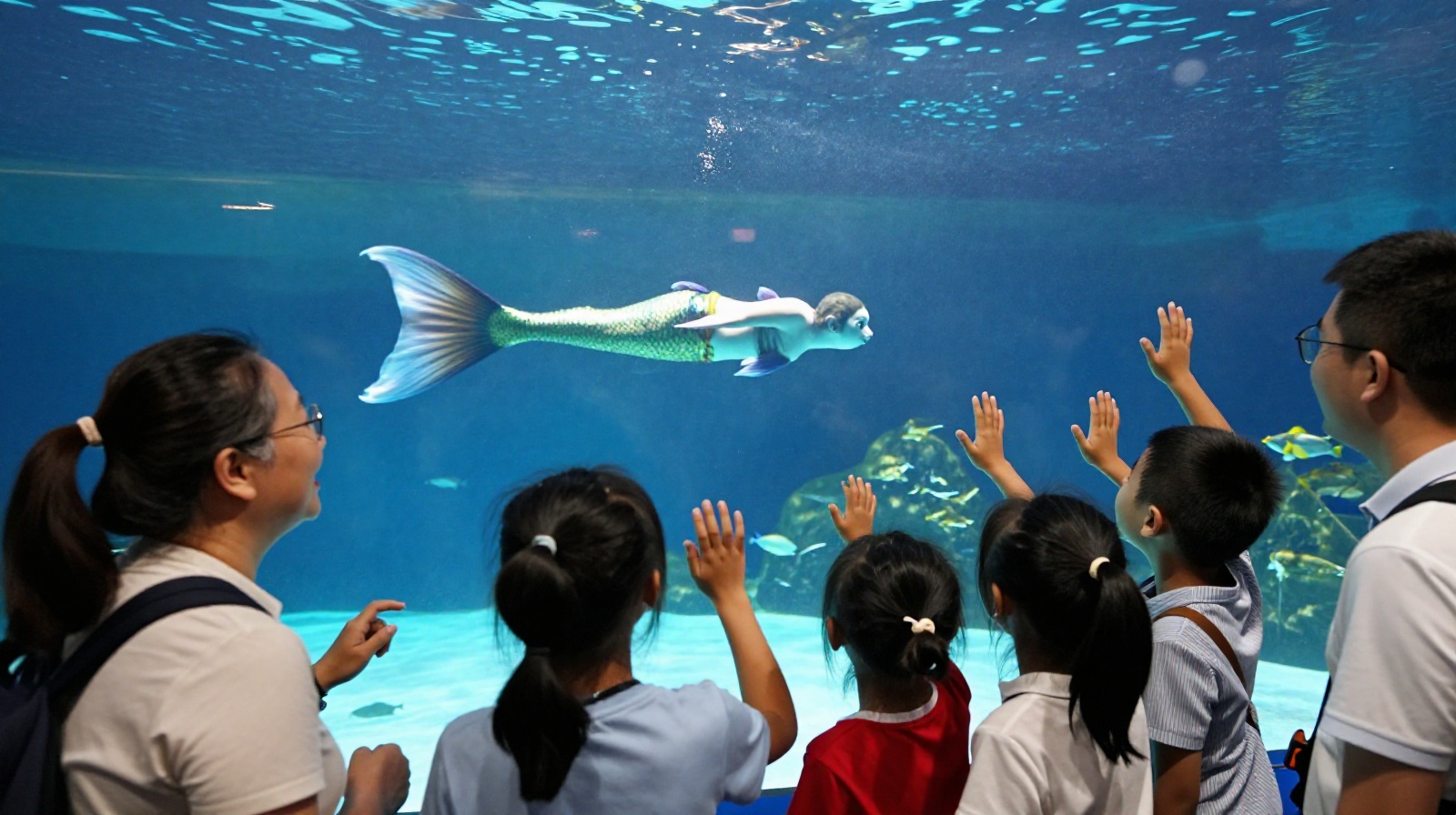 Tourists watching a mermaid perform inside a large aquarium tank in Xi'an