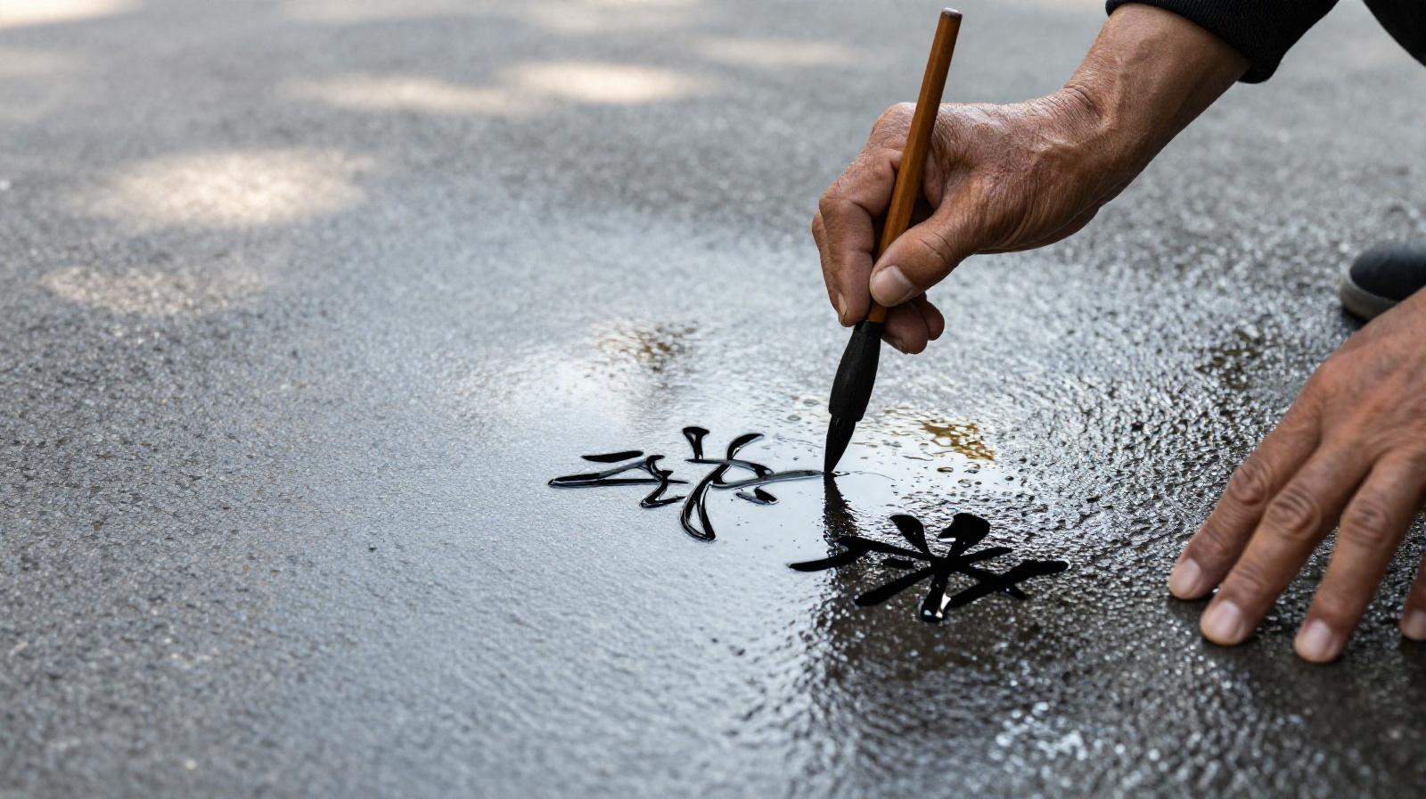 Close-up of elderly street cleaner writing poetry in water on wet pavement at dawn