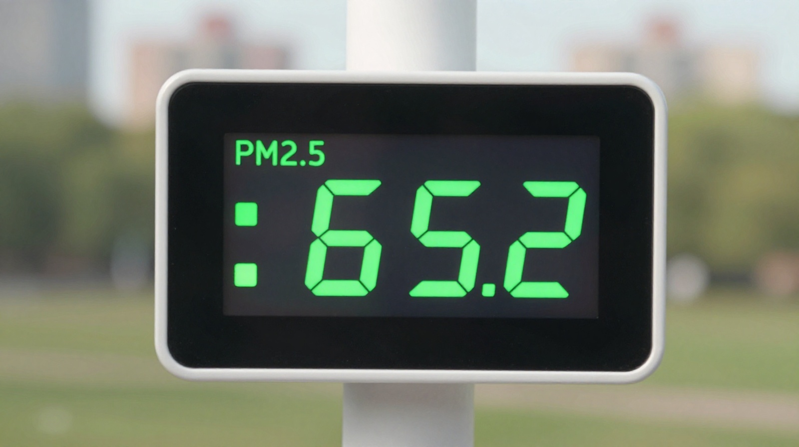 Digital air quality monitor displaying low PM2.5 levels in a Chinese urban park