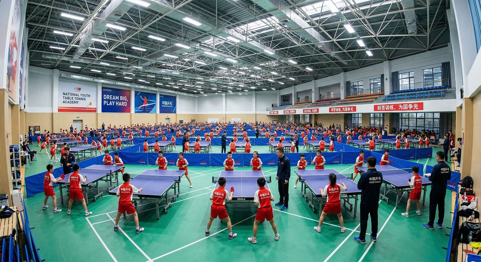 Young athletes in red uniforms training intensely on table tennis courts inside a large indoor sports center in China