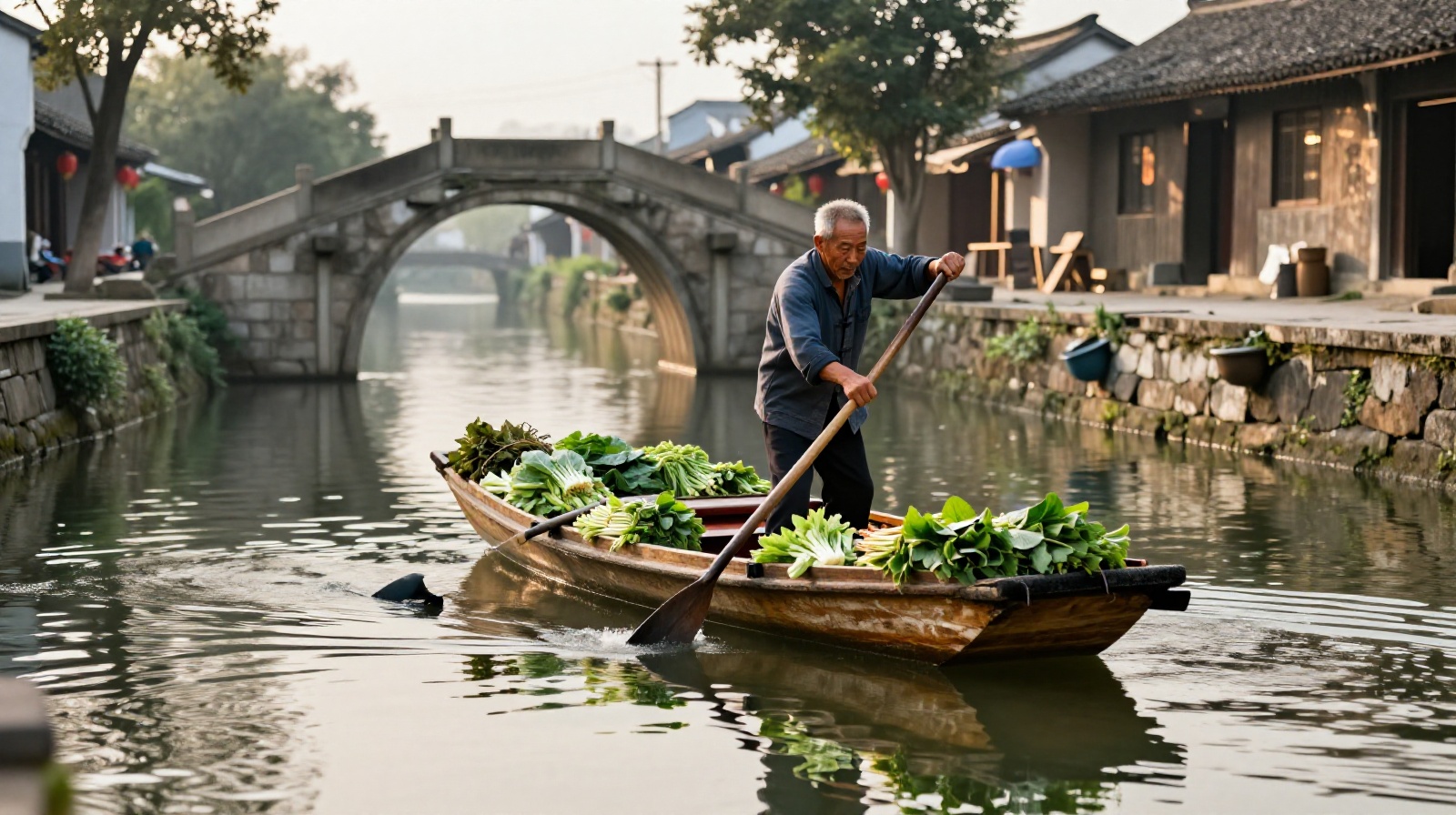 An elderly local resident rowing a wooden boat filled with fresh produce along a historic canal in a Chinese water town during early morning hours.