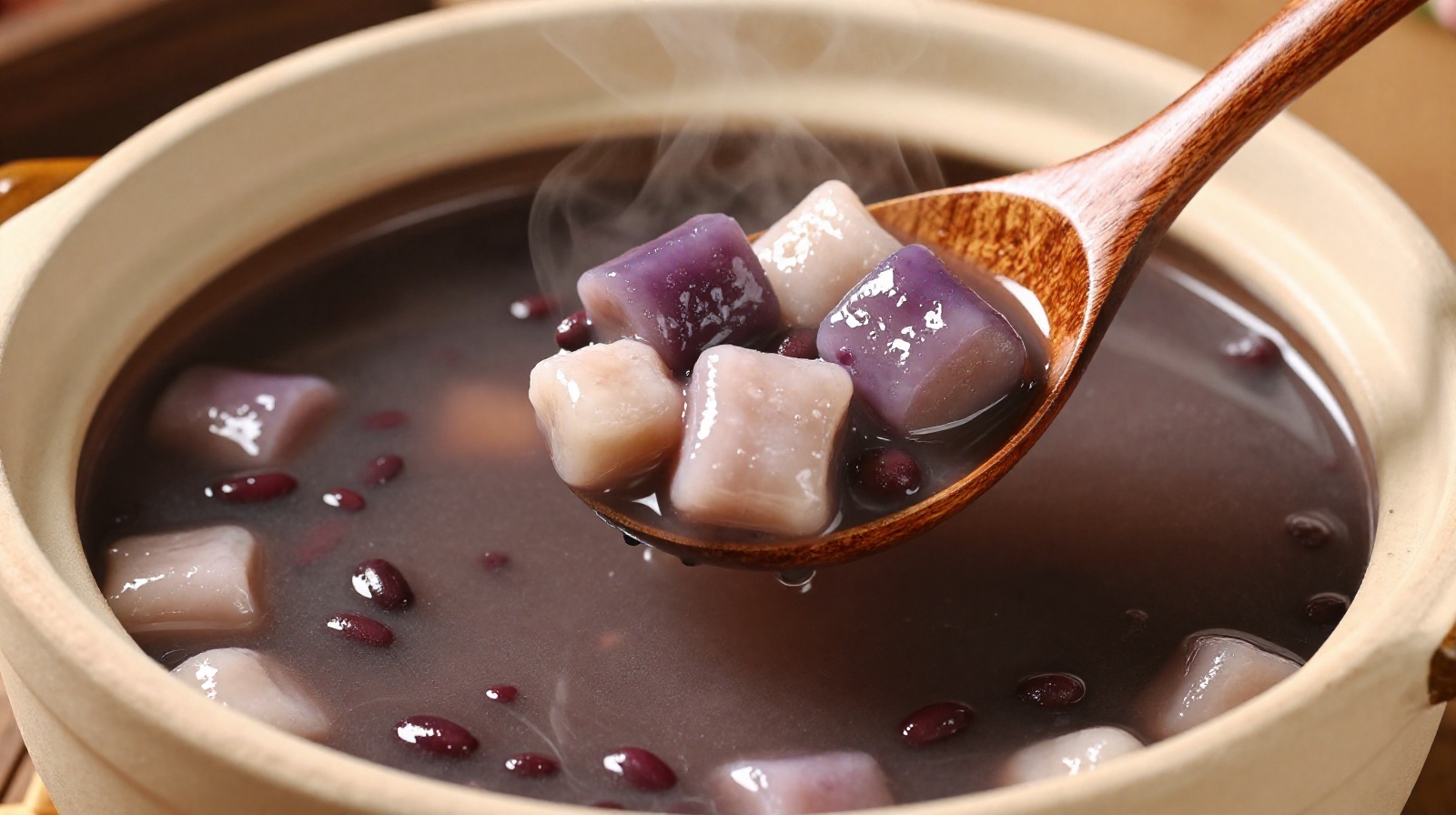 A close-up of steaming red bean sweet soup (tong sui) with taro balls being served in a traditional clay pot at a Guangzhou street stall.