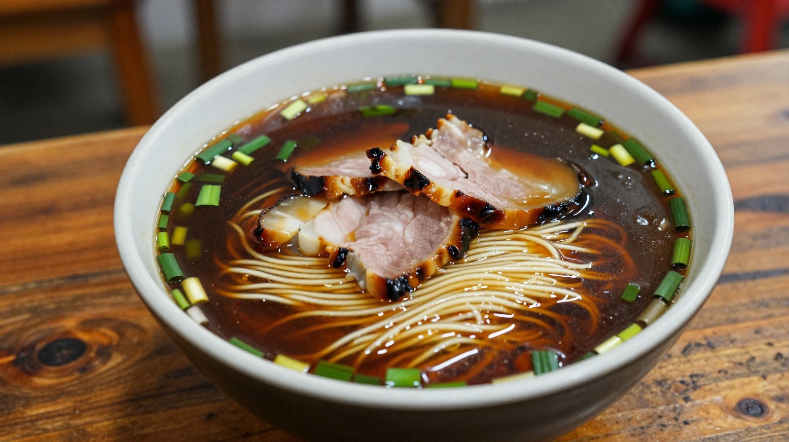 A close-up photo of a bowl of sweet soy sauce noodle soup typical of Suzhou, China, featuring dark glossy broth and green onions.