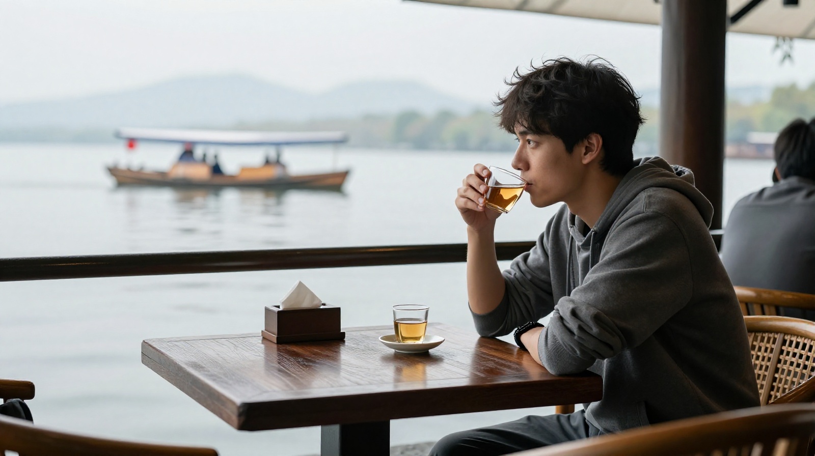 Foreign traveler enjoying tea at a lakeside cafe with a view of West Lake