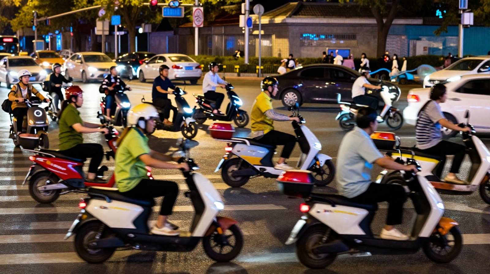 Electric scooter delivery riders navigating busy Beijing streets at night