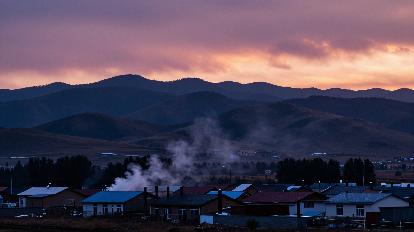 Sunset over the Qilian mountains with smoke rising from homes in a Qinghai village