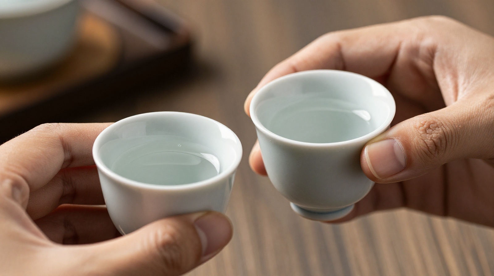 Demonstration of Chinese drinking etiquette where one person lowers their glass below another's to show respect during a toast.