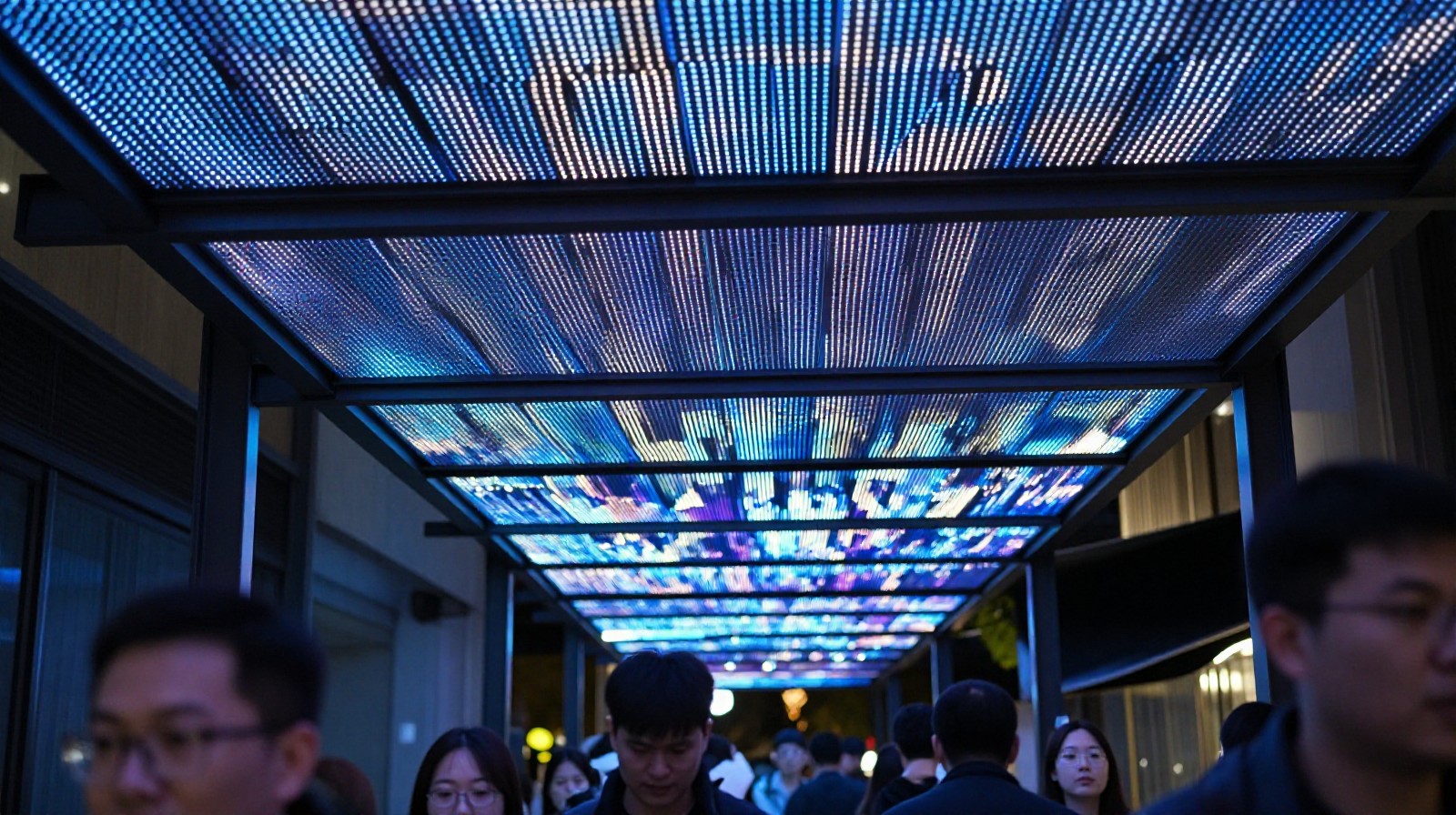 Looking up at the 80,000-screen LED canopy in Suzhou Industrial Park, showing the grid structure against the night sky with pedestrians below.
