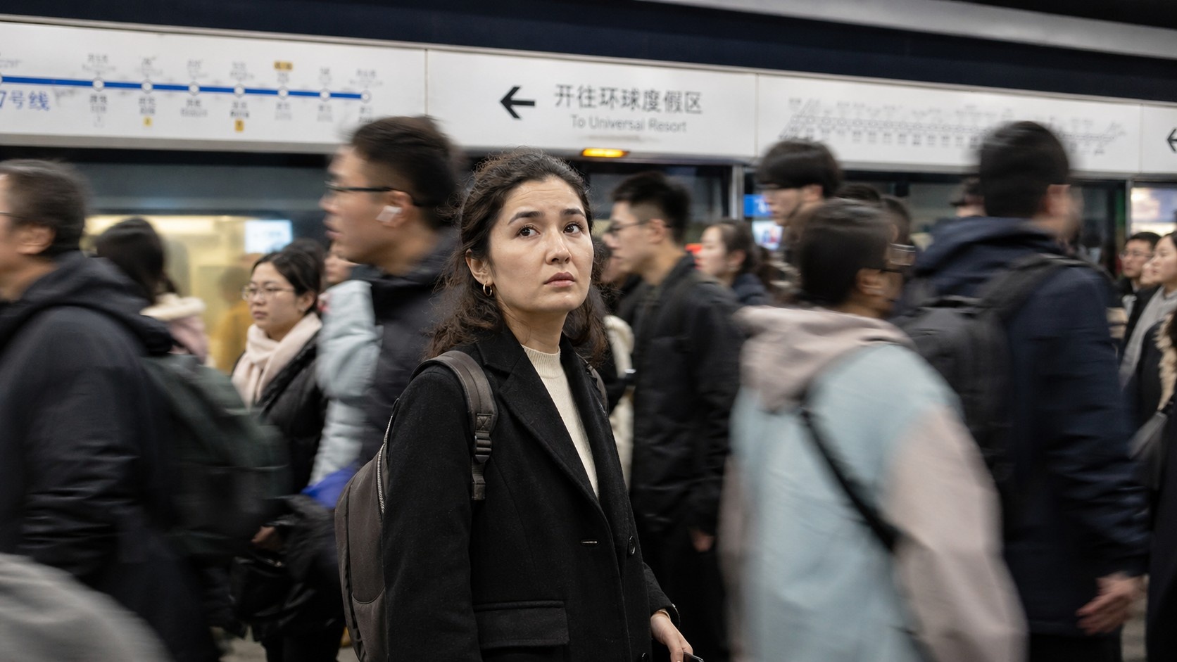 A Uyghur dancer standing on a crowded Beijing subway platform during morning rush hour