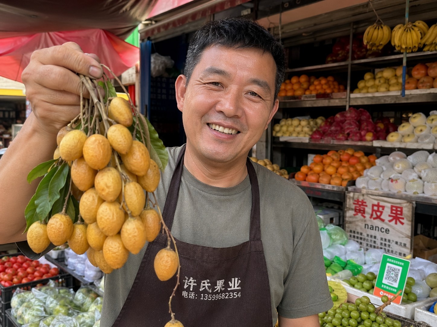 A smiling fruit seller in China presenting unique local fruits to customers at an open-air market