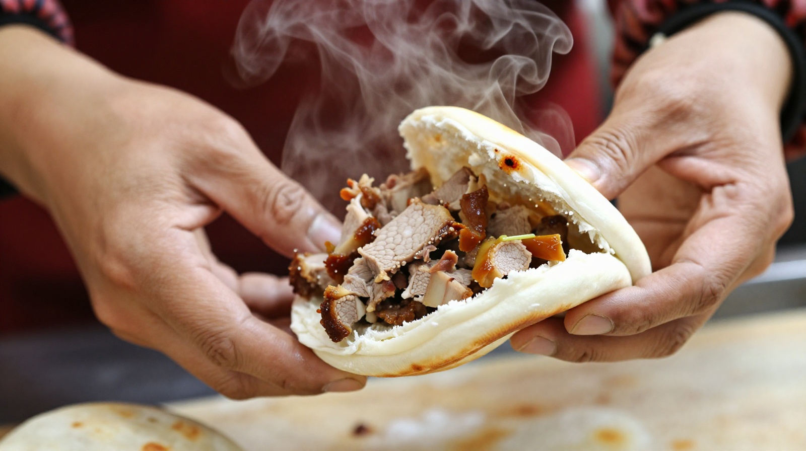 Close-up of hands making Roujiao, a Chinese street food consisting of a crispy bun stuffed with slow-cooked pork