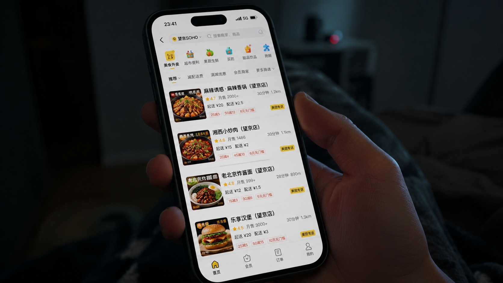 Close-up of a smartphone displaying a Chinese food delivery app interface in a dimly lit apartment at night