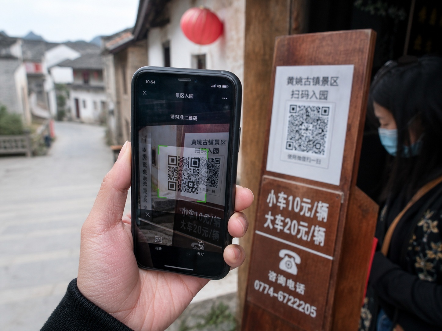 A tourist using a mobile payment app to scan a QR code for entry at a rural destination, demonstrating China's digital tourism ecosystem.