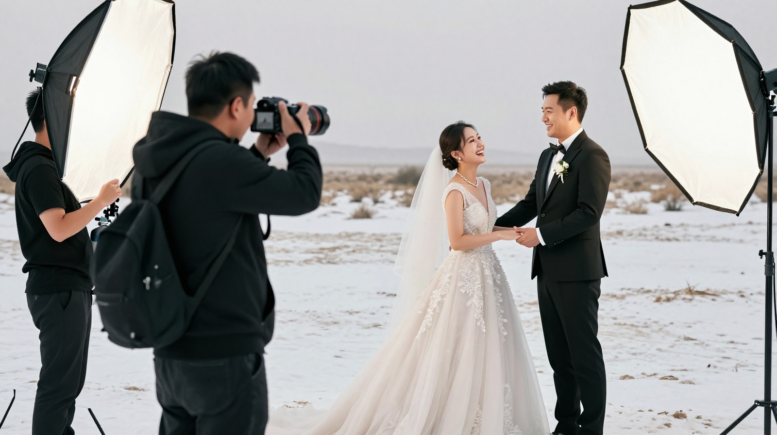 Behind-the-scenes view of a professional wedding photoshoot crew assisting a couple in extreme weather conditions with equipment like oxygen tanks and reflectors.