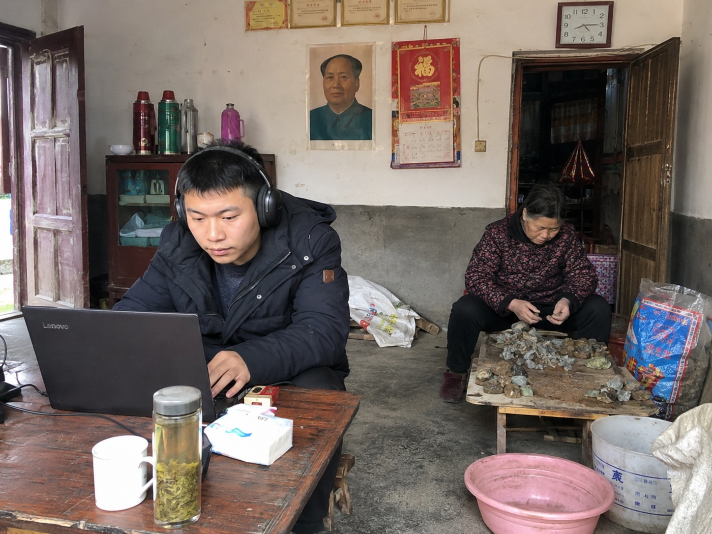 Young entrepreneur managing digital accounts for his family's jade business in their rural home.