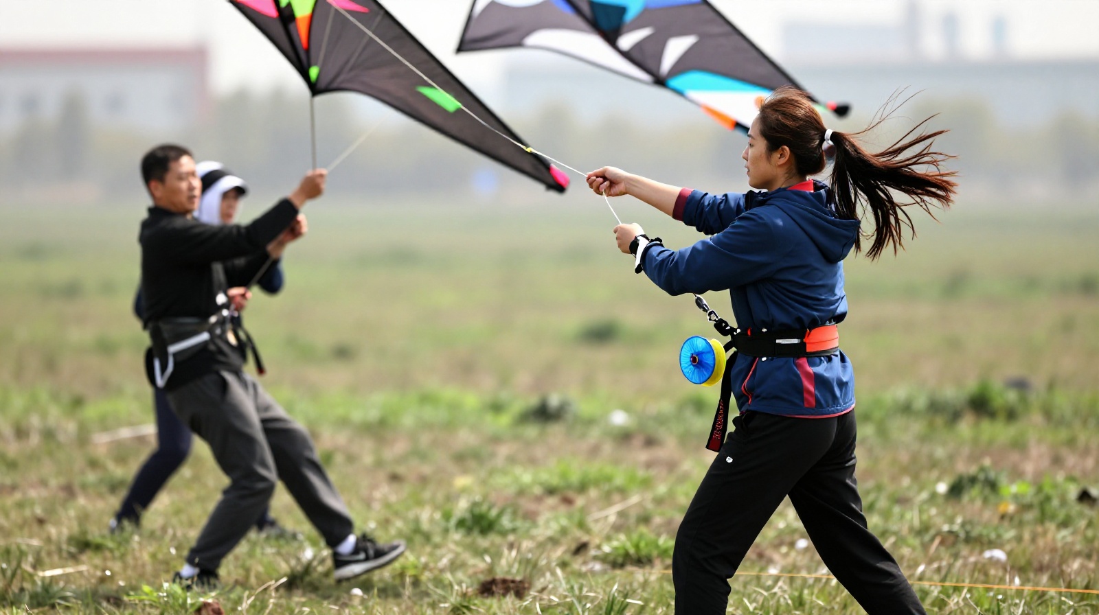 Enthusiasts working as a team to control a large kite in strong wind at a public park.