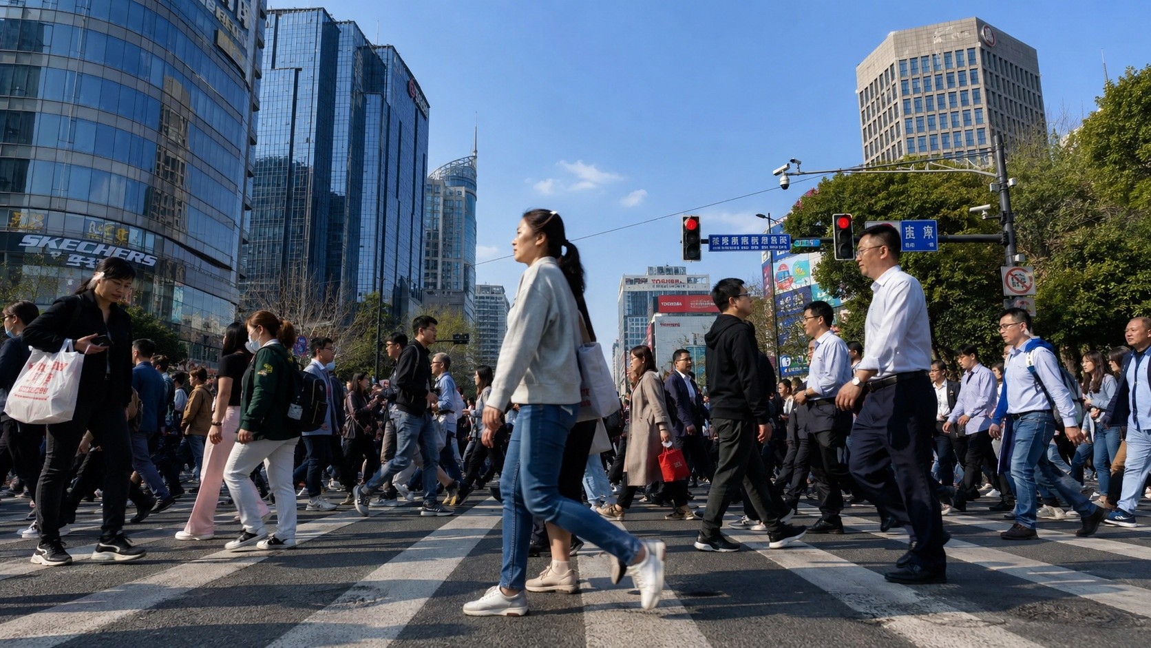 A large crowd of pedestrians crossing a street in a Chinese city, showing the collective movement and density of urban life.
