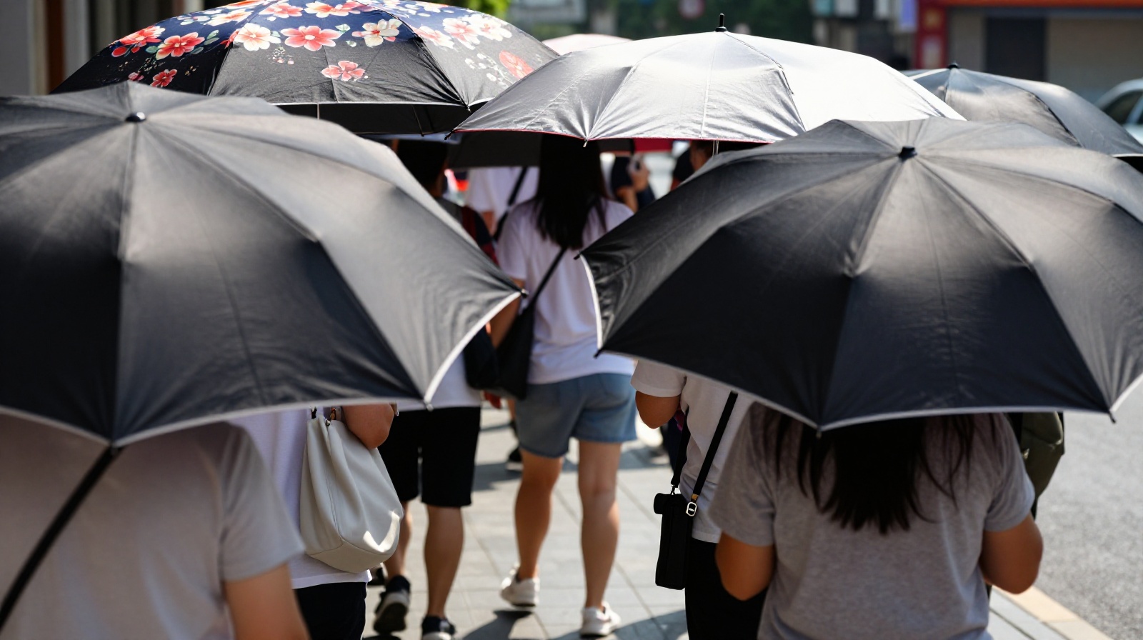 Crowded Chinese sidewalk in summer with many people holding sun umbrellas for shade