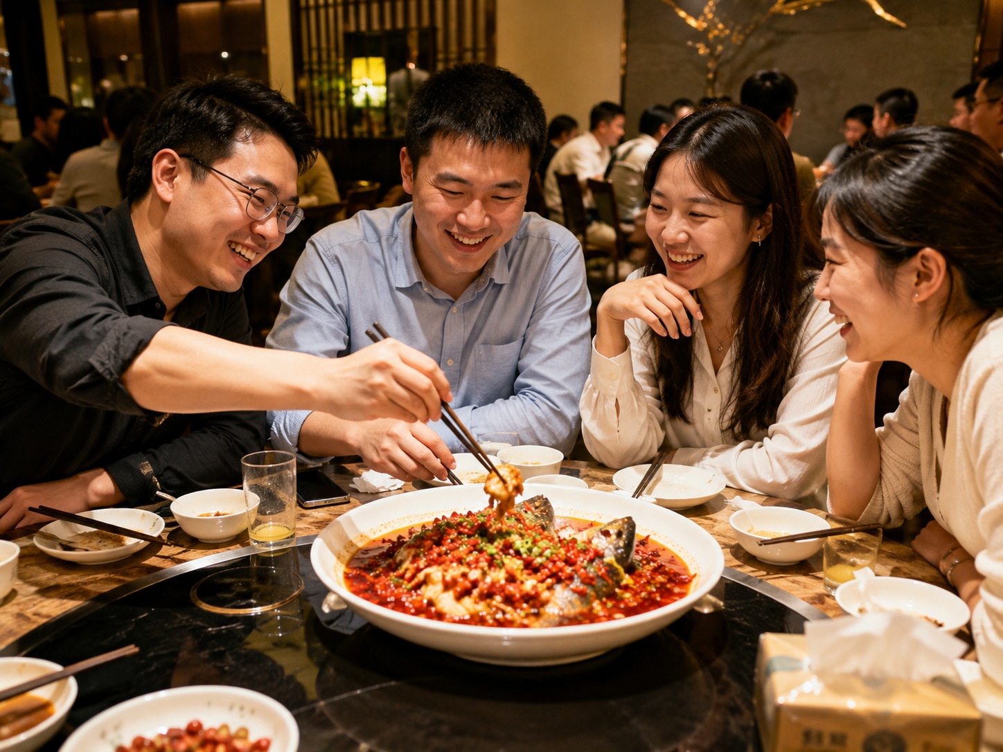 Young Chinese professionals sharing a meal and laughing at a restaurant table.