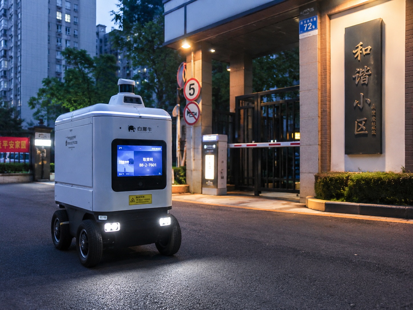A white autonomous delivery bot waiting at a gated entrance in a Chinese residential area, showing its digital interface to a resident.