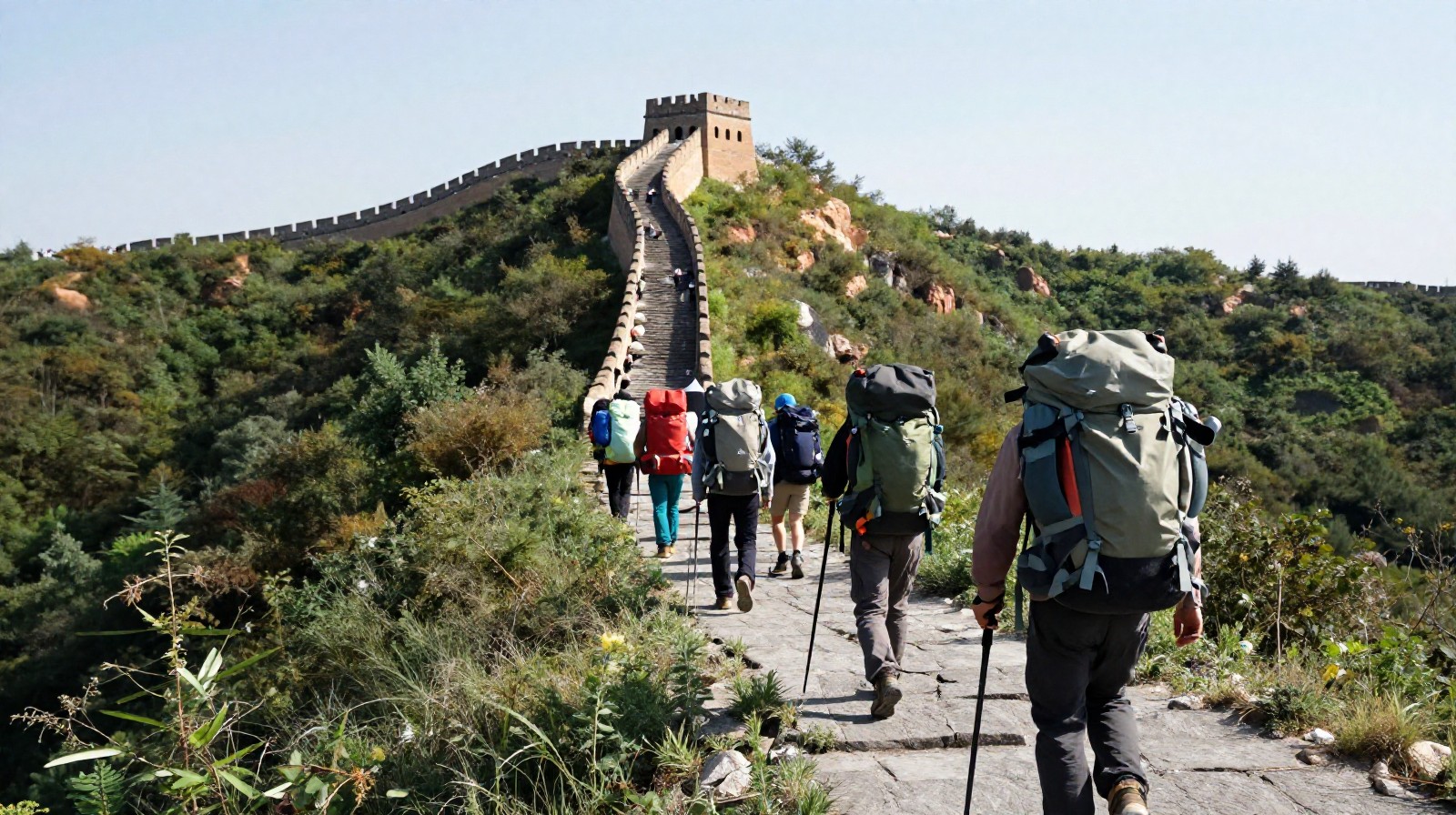 Hikers with large backpacks hiking up a narrow mountain path towards the Wild Great Wall.