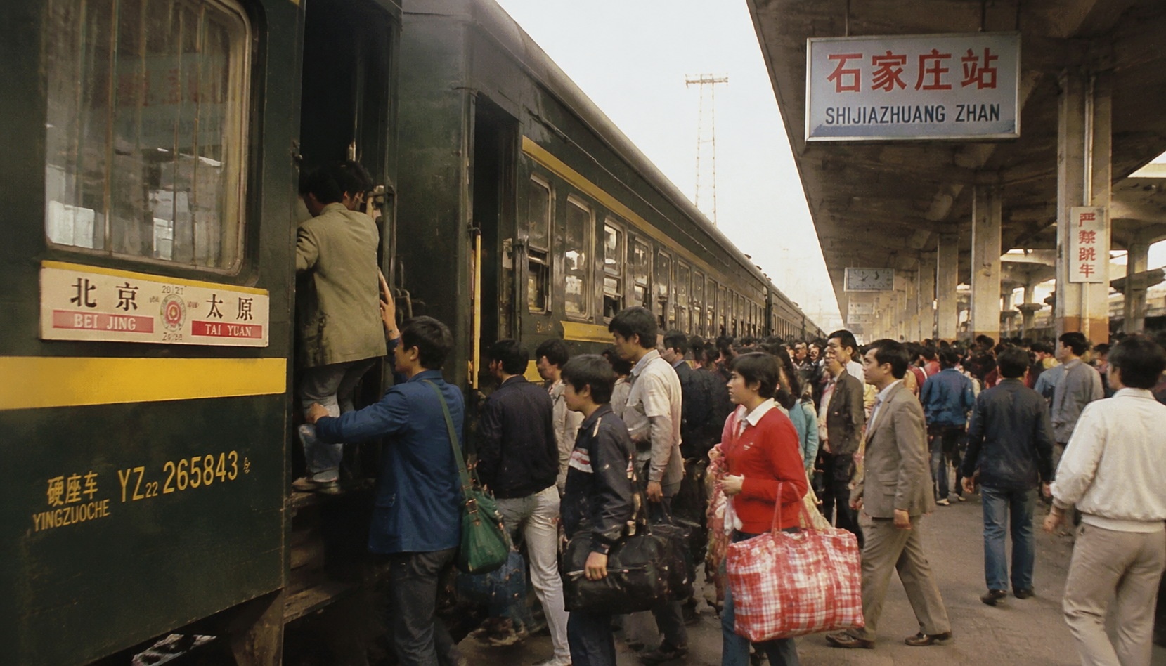 A vintage green train at a Chinese railway station in the 1990s, with passengers boarding, representing the old era of China's railway.