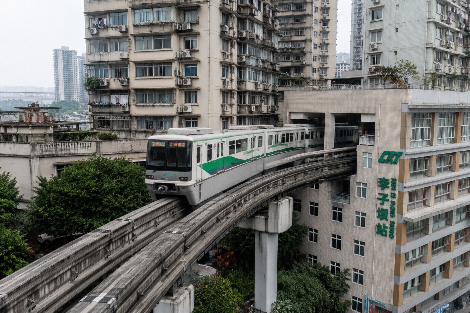 Chongqing's famous Line 2 light rail train navigating a curve near a high-rise apartment building, showcasing the city's unique urban design.