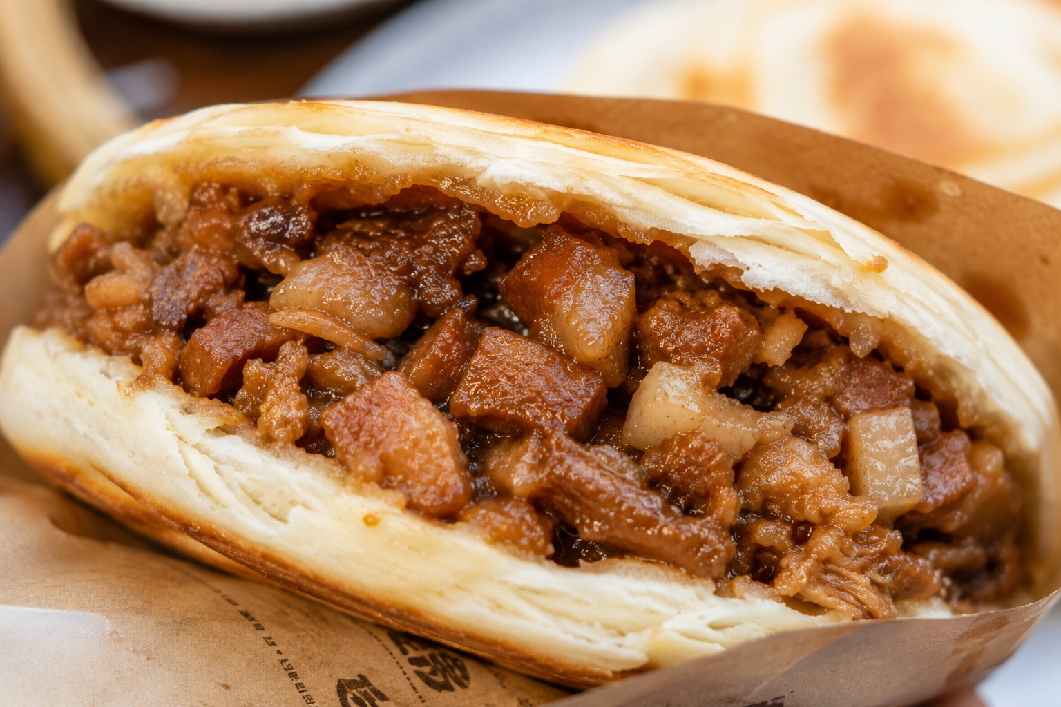 Close-up cross-section of a fresh Roujiamo showing the crispy flatbread and juicy braised pork filling.
