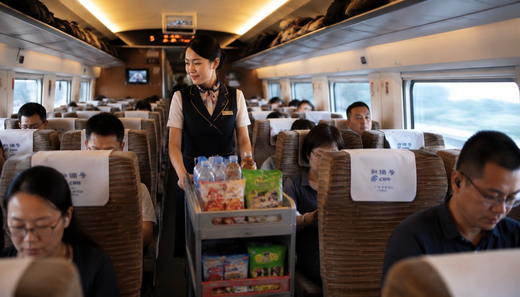 A Chinese high-speed train attendant pushing a snack cart through the carriage.
