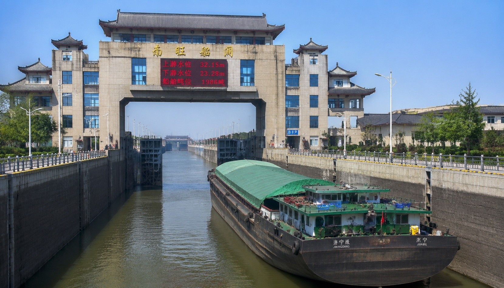 A modern lock on the Grand Canal with a barge waiting to pass; digital signage and traditional design elements are visible.