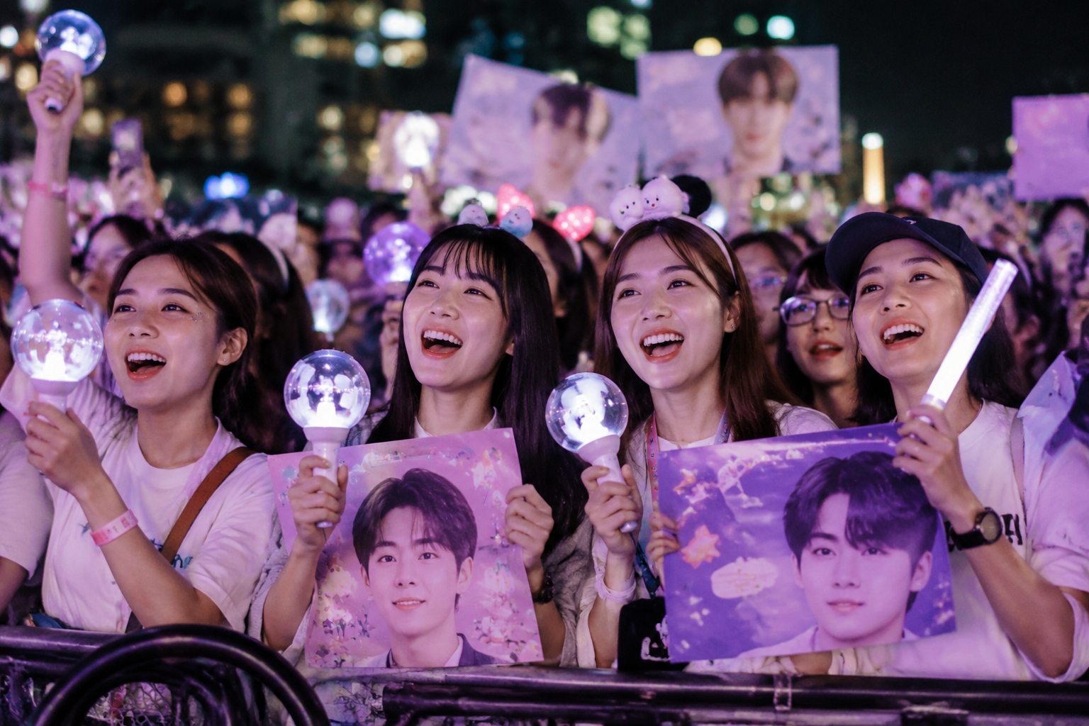 Young Chinese fans at an idol fan meeting, holding lightsticks and signs