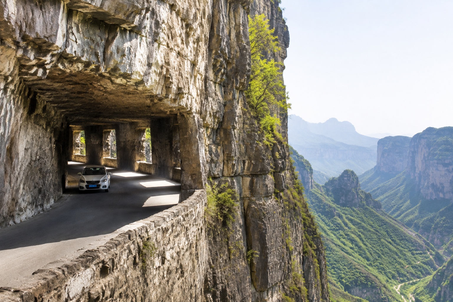 Car driving through Guo Liang Tunnel Road, a cliff-highway in Taihang Mountains with window openings revealing valley views