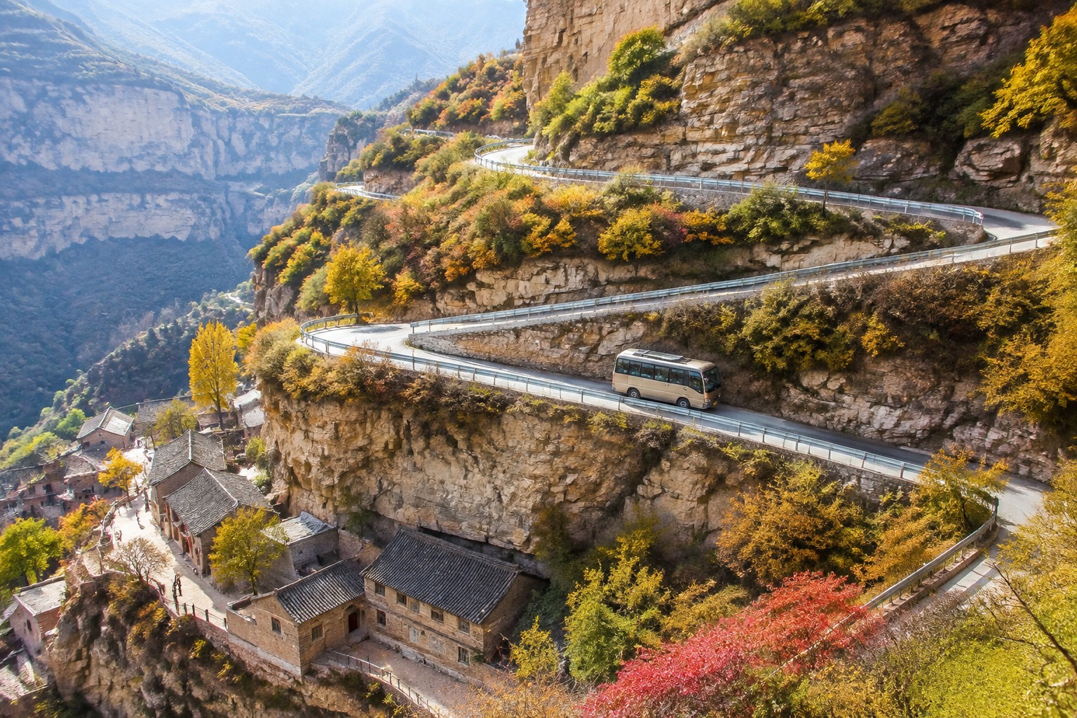 Switchback cliff road with guardrails in Taihang Mountains in autumn, with village visible below