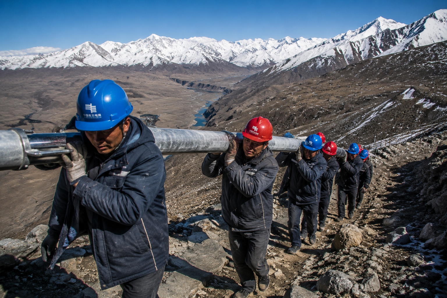 Chinese electrical workers carrying a power pole through the mountains of Tibet during grid extension in remote areas
