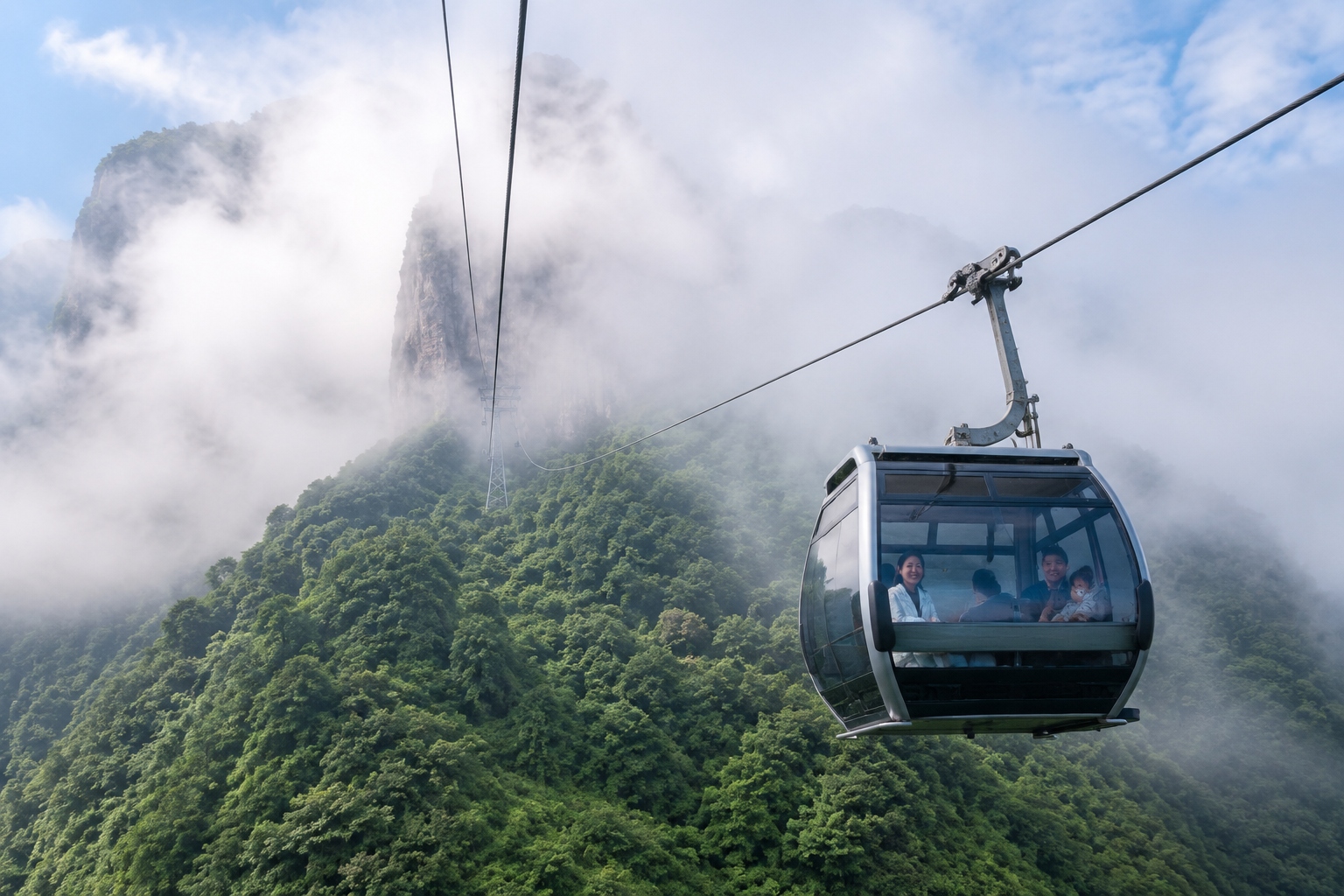 Cable car descending over forested slopes of Fanjingshan during a foggy morning, with a glimpse of the stone summit in the distance.