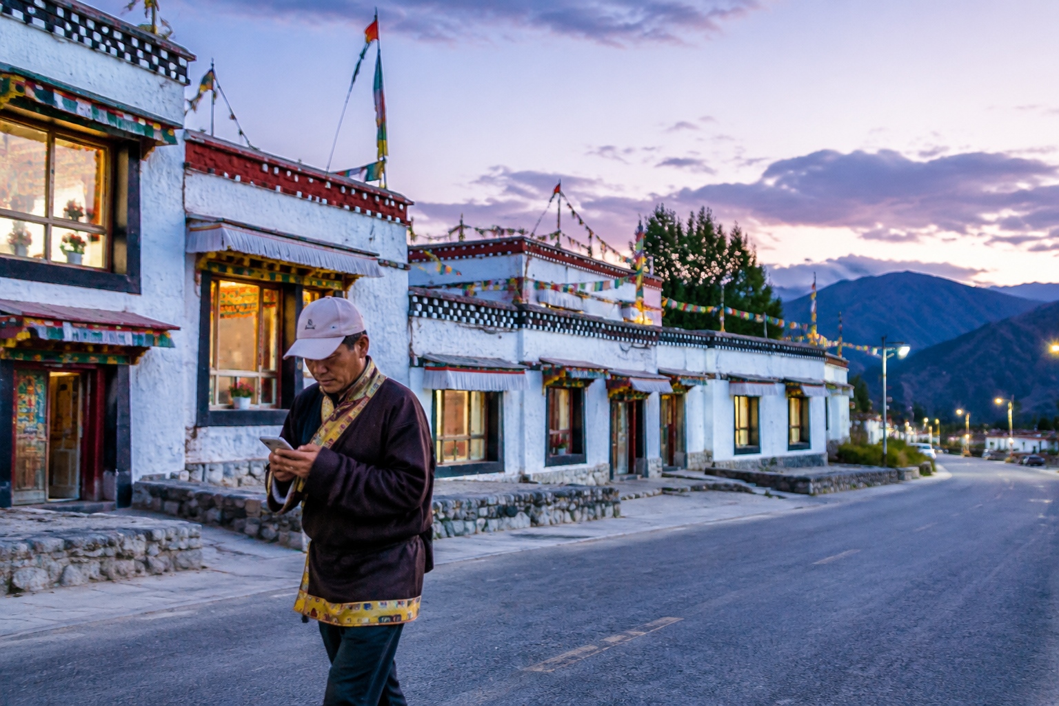 Tibetan guide walking in the new village at dusk with prayer flags