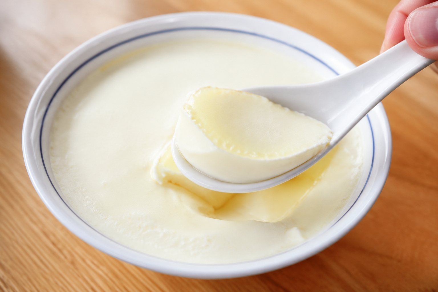 Bowl of silky Cantonese double-skin milk dessert with a spoon, a classic Guangzhou sweet soup