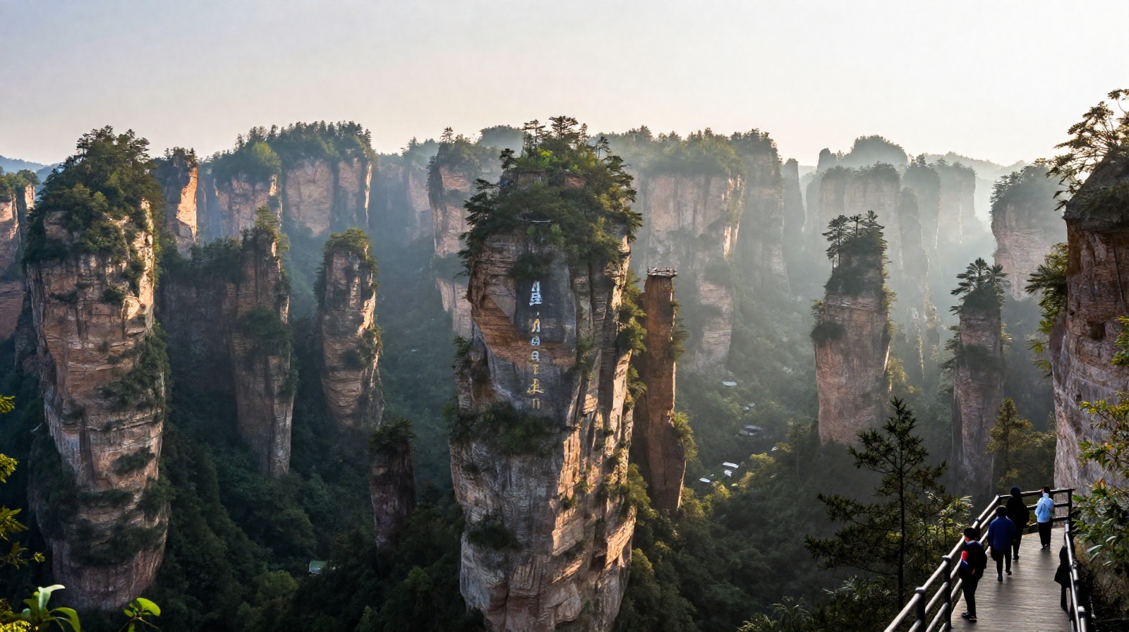 Avatar Hallelujah Mountain pillar in Zhangjiajie with tourists on boardwalk at sunrise, showing scale of the floating peaks.