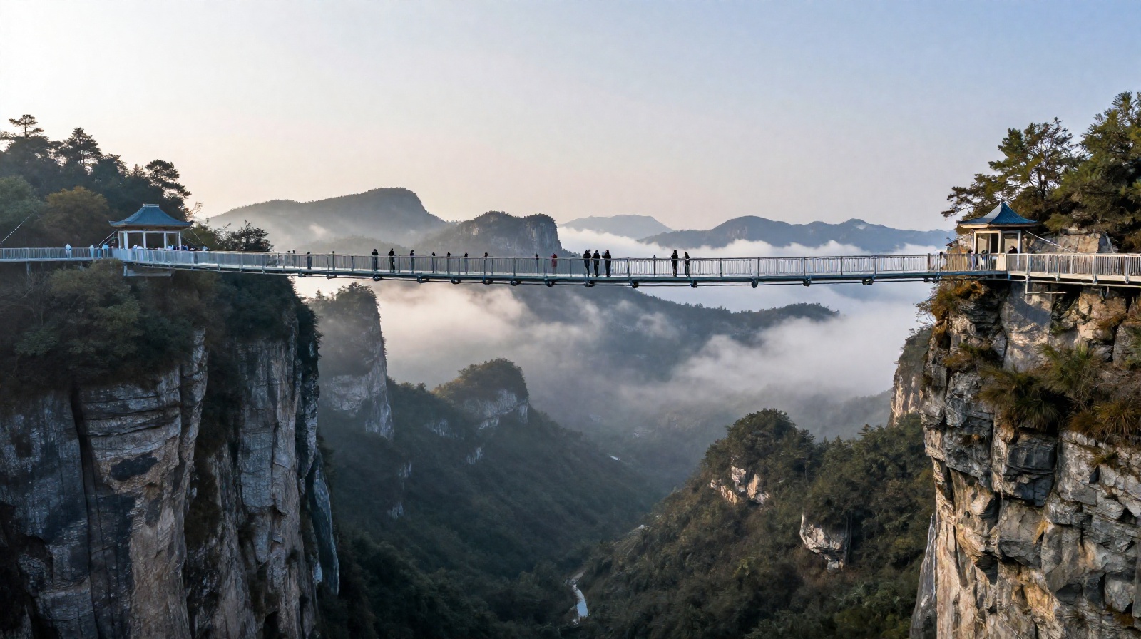 Zhangjiajie Grand Canyon Glass Bridge in early morning with mist and mountains in background.