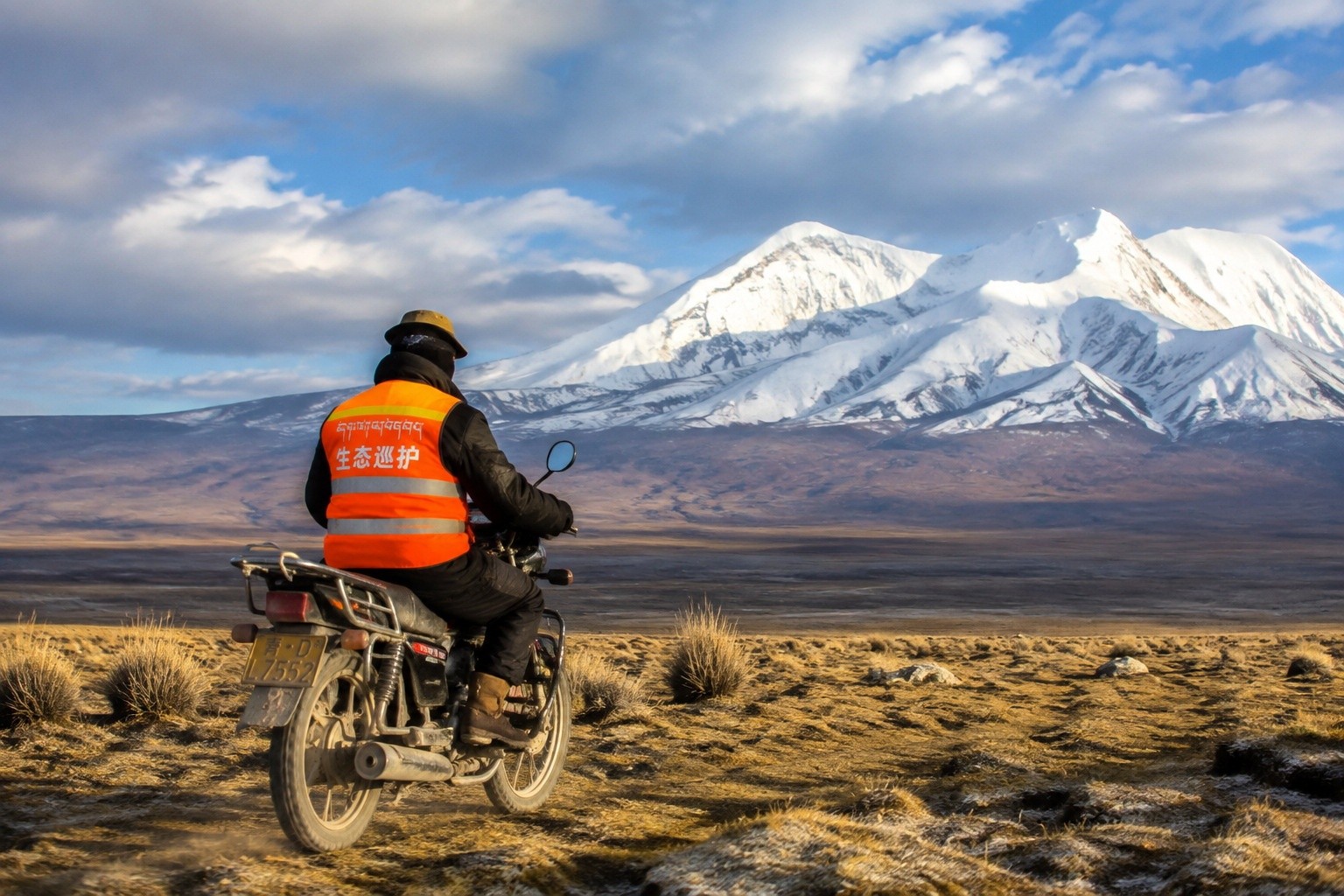 Tibetan eco-guardian riding motorcycle on the Qinghai plateau during a patrol in Sanjiangyuan National Park