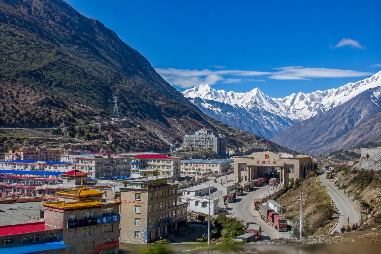 Gyirong town and the port area in southern Tibet with freight trucks parked along the road, surrounded by Himalayan mountains
