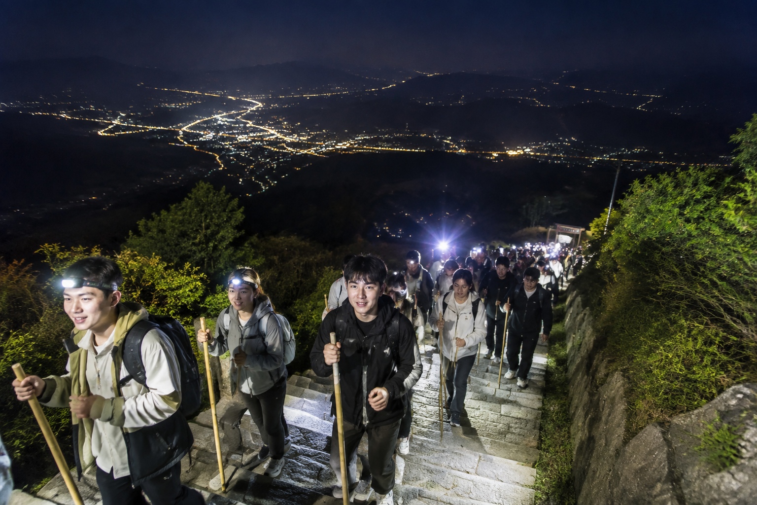 Night hikers climbing Mount Tai's stone steps with flashlights and headlamps