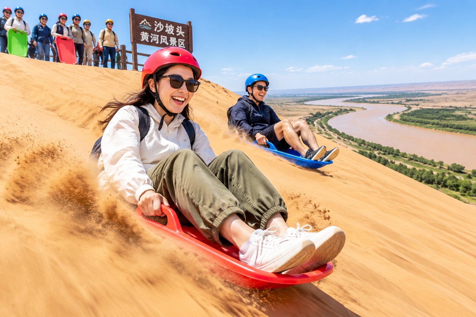 Tourists sand-sledding down steep dunes at Shapotou, with the Yellow River in the distance.