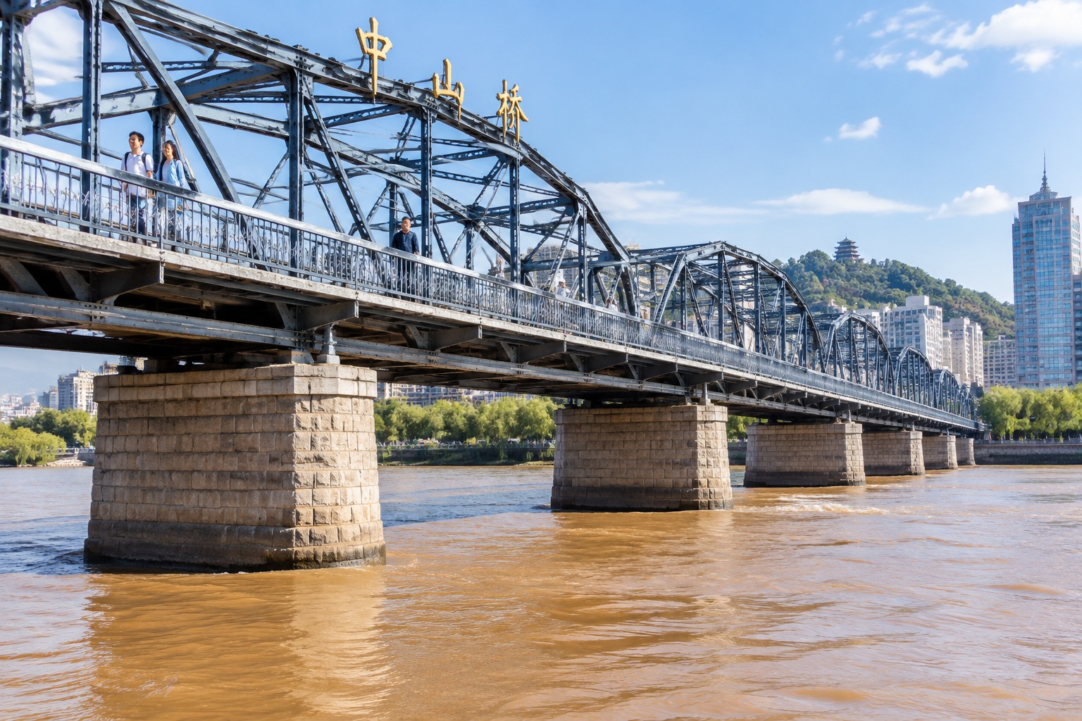 Zhongshan Bridge in Lanzhou seen from the riverbank at water level, showing its steel trusses, stone piers and pedestrians crossing above