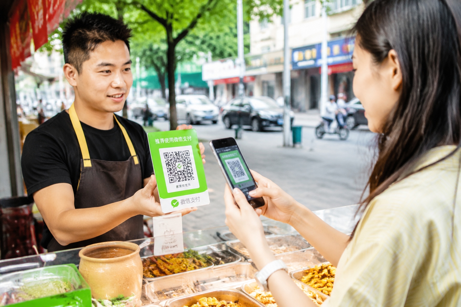 Close-up of a customer using WeChat Pay on a smartphone to scan a QR code at a street food vendor in China